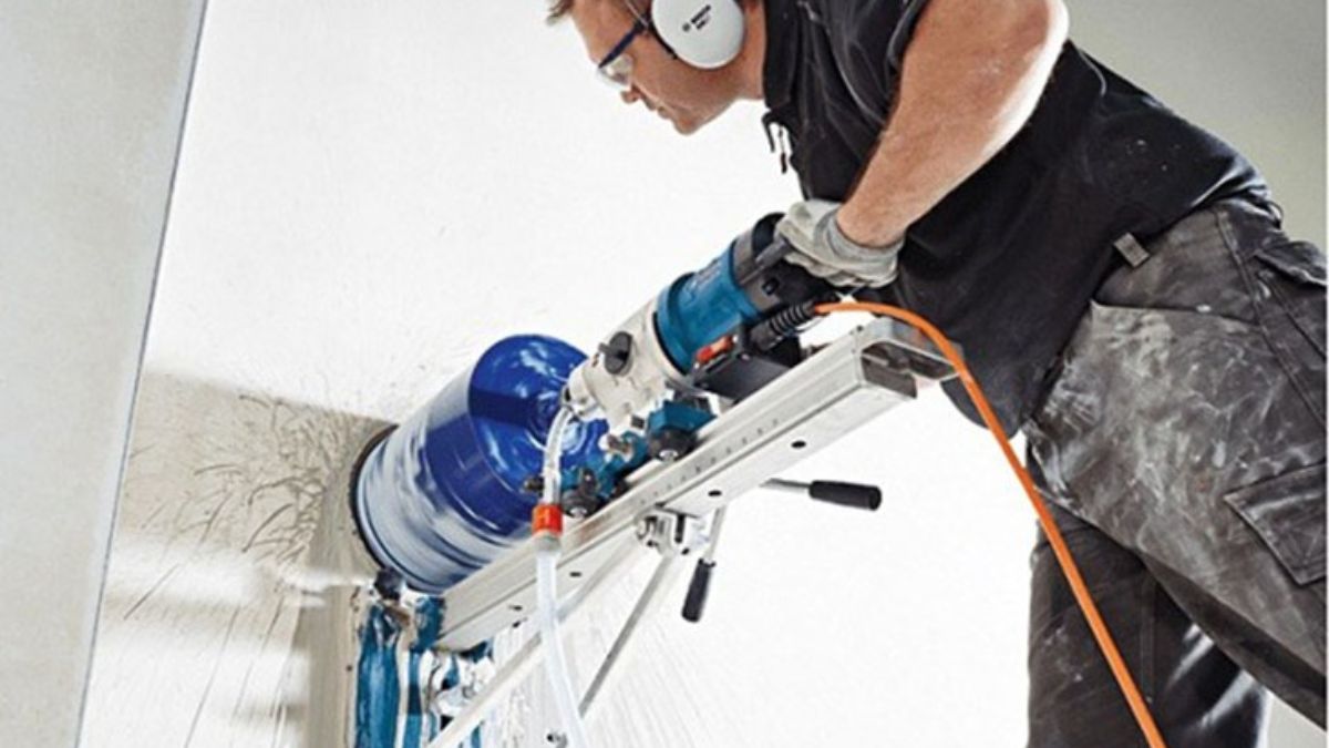 "Thợ thi công khoan rút lõi bê tông bằng máy khoan công nghiệp gắn tường, đảm bảo độ chính xác và an toàn trong xây dựng."