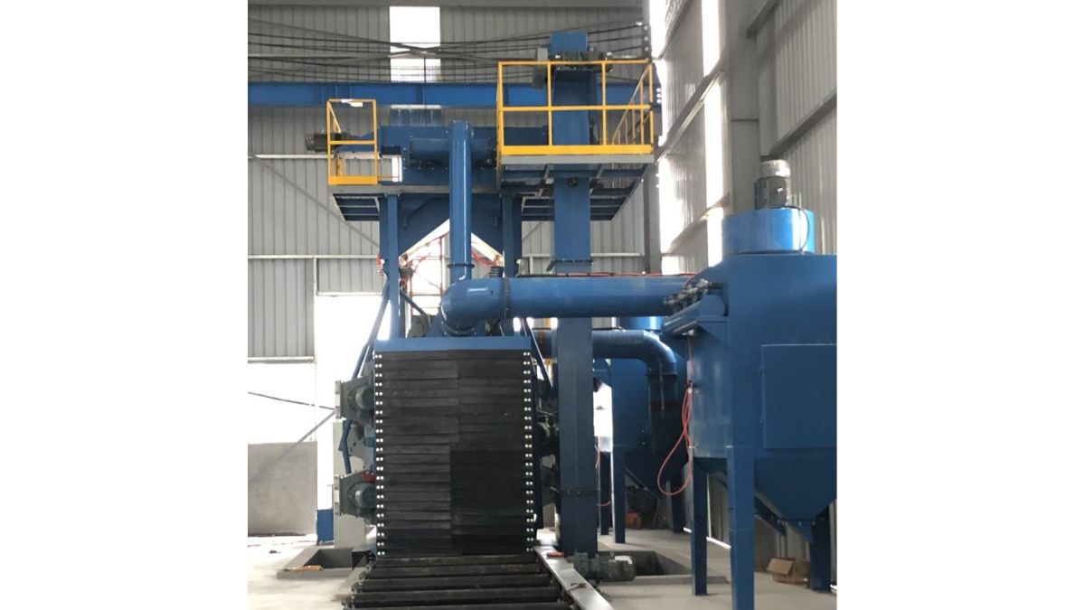 "Hình ảnh máy phun bi làm sạch bề mặt thép tấm công nghiệp, thiết bị hiện đại trong nhà xưởng, giúp loại bỏ rỉ sét và tăng độ bám dính cho sơn phủ kết cấu thép."