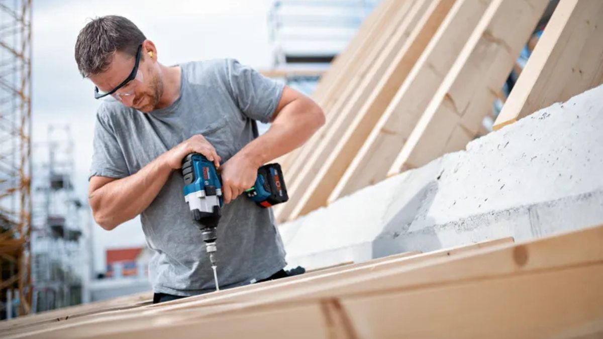 "Thợ xây dựng sử dụng máy siết bu lông Bosch Professional 18V thi công khung mái gỗ, công cụ mạnh mẽ giúp siết vít nhanh chóng và an toàn"