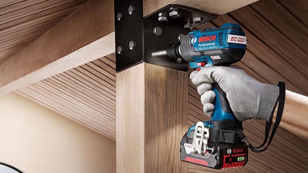 "Máy siết bu lông Bosch Professional 18V EC motor đang siết chặt bu lông vào khung thép gắn trên cột gỗ, công cụ mạnh mẽ cho thi công xây dựng và lắp ráp"