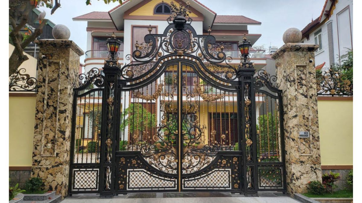 Cổng sắt mỹ thuật uốn nghệ thuật với thiết kế hoa văn tinh xảo, kết hợp đèn chiếu sáng cổ điển, tạo nên vẻ đẹp sang trọng và đẳng cấp cho không gian nhà ở
