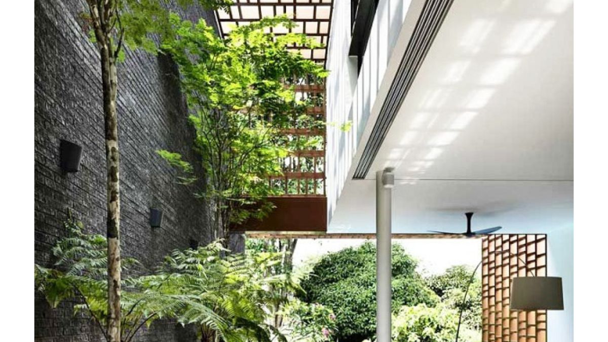 Không gian giếng trời với cây xanh, ánh sáng tự nhiên chiếu vào qua mái lưới, tạo sự thoáng đãng và gần gũi với thiên nhiên cho ngôi nhà