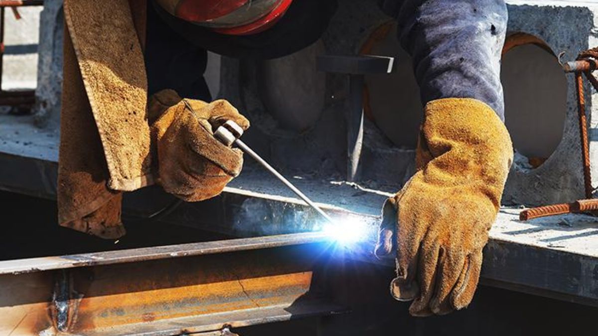 "Thợ hàn đang hàn kết cấu thép với que hàn hồ quang điện, minh họa kỹ thuật hàn kim loại trong xây dựng công trình"