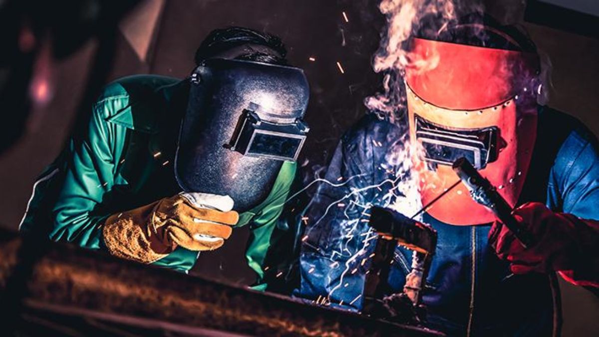 "Thợ hàn cơ khí đang thực hiện kỹ thuật hàn điện với mũ bảo hộ và găng tay bảo hộ, tạo ra tia lửa sáng trong quá trình hàn kim loại"