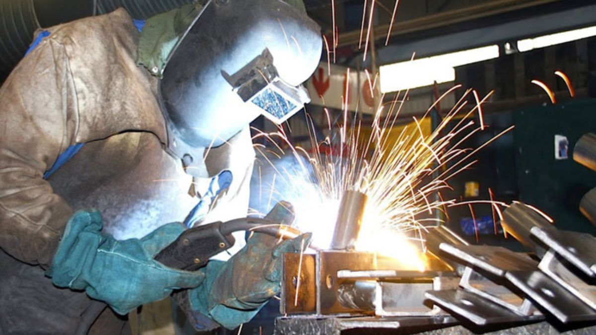 "Thợ hàn hồ quang tay trong xưởng cơ khí, đang hàn kim loại với tia lửa phát ra – đảm bảo an toàn lao động khi hàn."